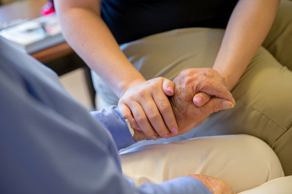 Caregiver and elderly woman holding hands