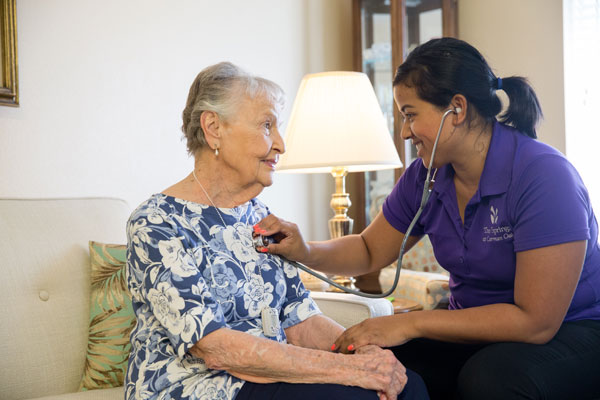 caregiver checking elderly woman's heart