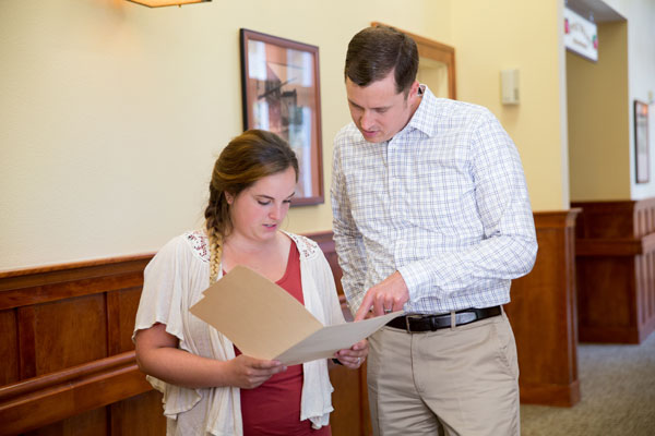 younger and man and woman looking at documents in a folder