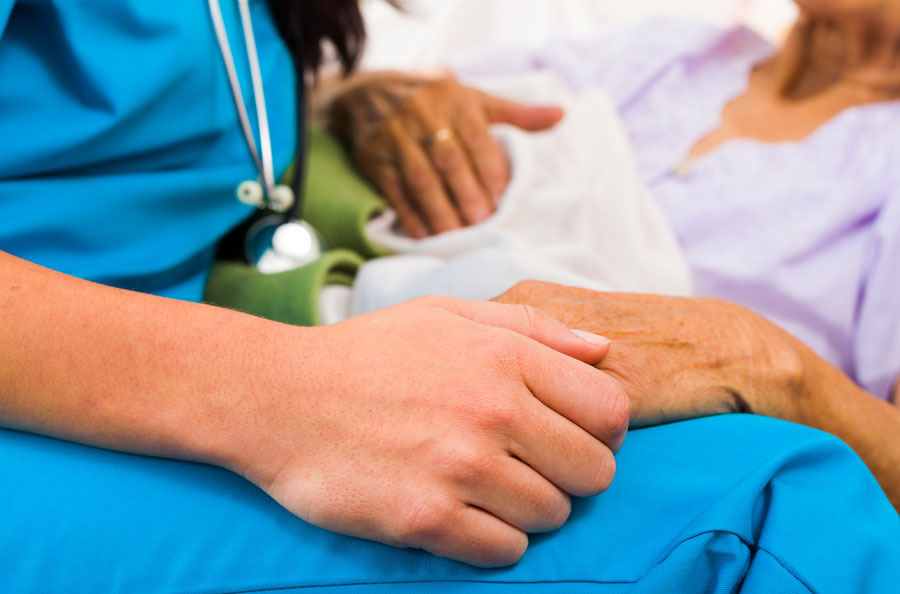 closeup of nurse holding an elderly woman's hand