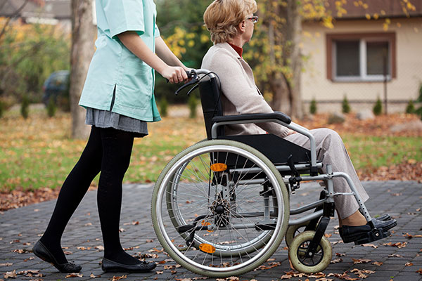 Woman pushing elderly woman in wheelchair