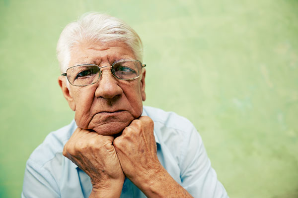 sad elderly man resting his head on his hands
