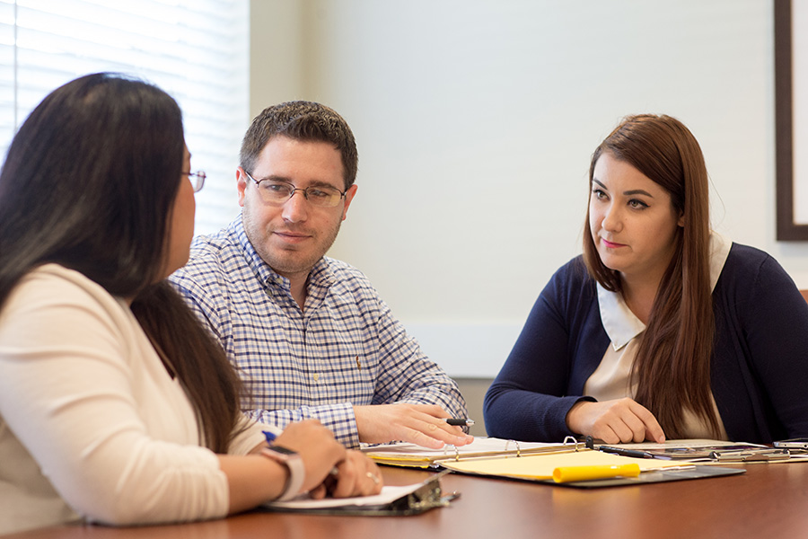 meeting - man and woman listening to woman talk at conference table