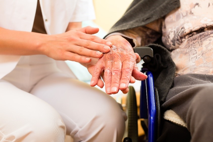 caregiver holding elderly woman's hand