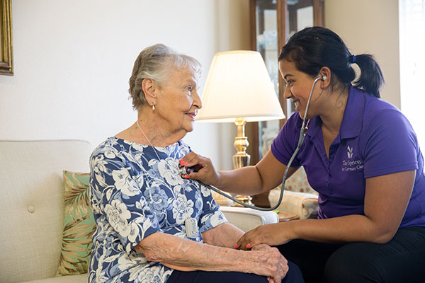 caregiver listenting to elderly woman's heart