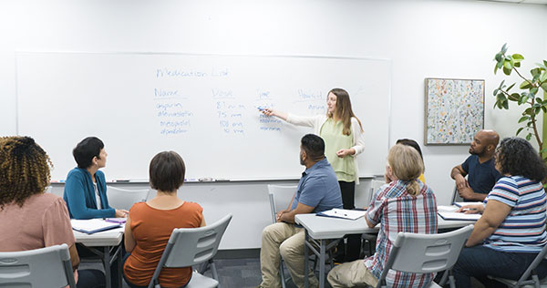 instructor teaching her class in front of a group of adult students