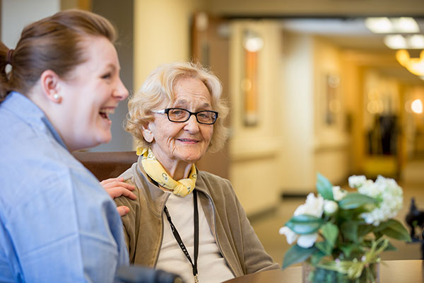 caregiver laughing and chatting with elderly woman