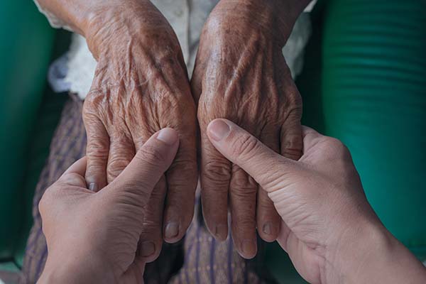 young and elderly woman holding hands